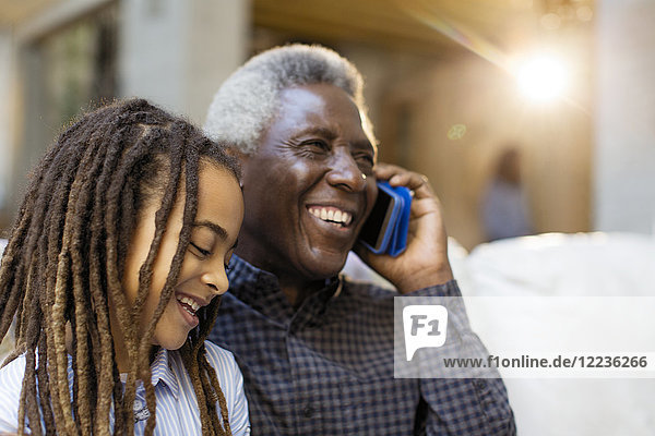 Glücklicher Großvater und Enkelin im Gespräch am Handy