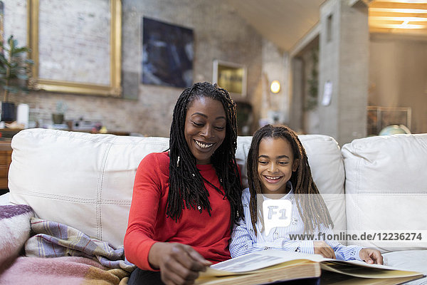 Mother and daughter looking at photo album on sofa