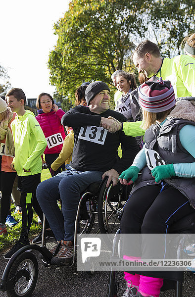 Mann im Rollstuhl schüttelt Hände mit Läufer in der Menge beim Charity-Rennen