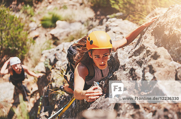 Focused  determined female rock climber hanging from rock