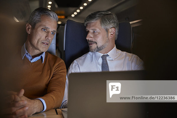 Geschäftsleute reden  nachts am Laptop im Personenzug arbeiten