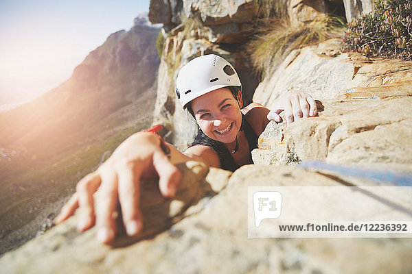 Portrait smiling  confident rock climber reaching for rock