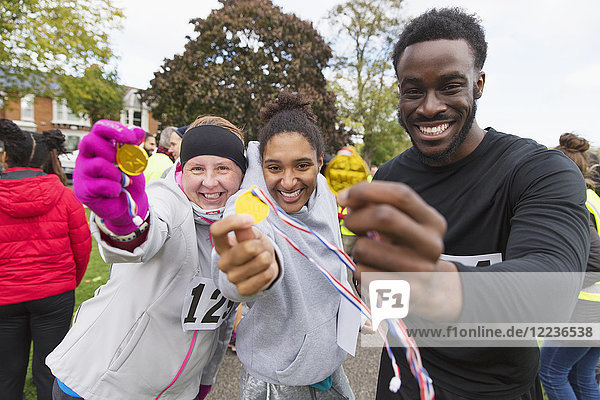 Portrait enthusiastic runners showing medals at charity run in park