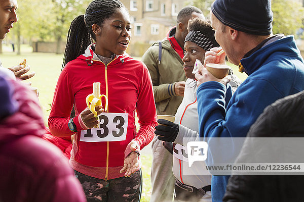 Runners drinking water and eating banana at charity race in park