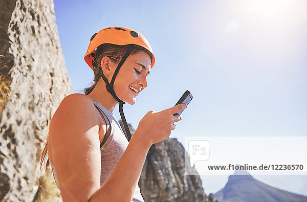 Lächelnde Klettererin mit Smartphone