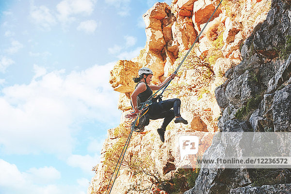 Weibliche Klettererin  die Felsen hinabsteigt