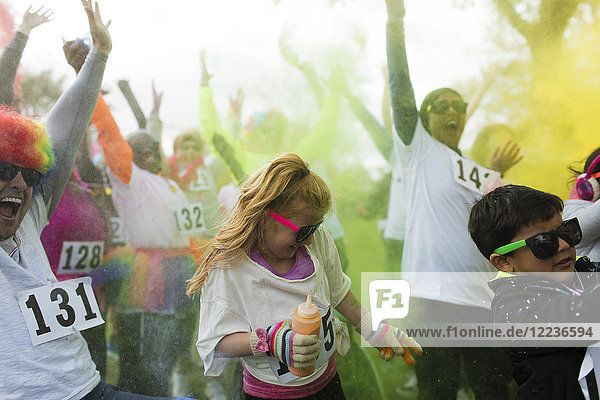 Playful crowd of runners throwing holi powder at charity run