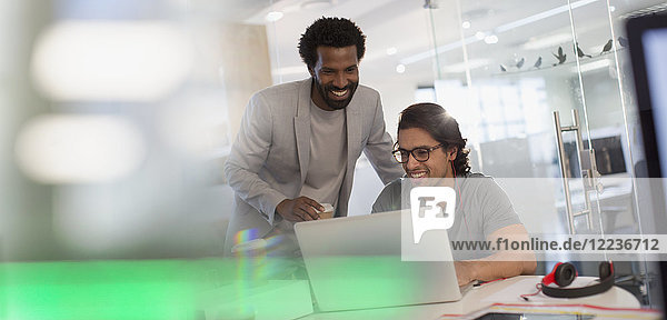 Smiling creative businessmen working at laptop in office