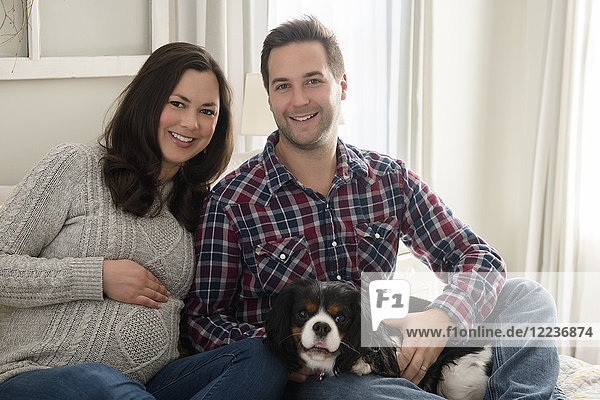Mid adult couple sitting on sofa with puppy