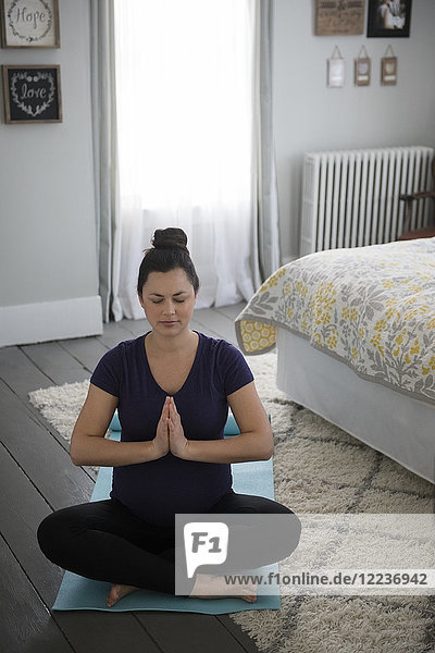 Schwangere Frau macht Yoga im Schlafzimmer