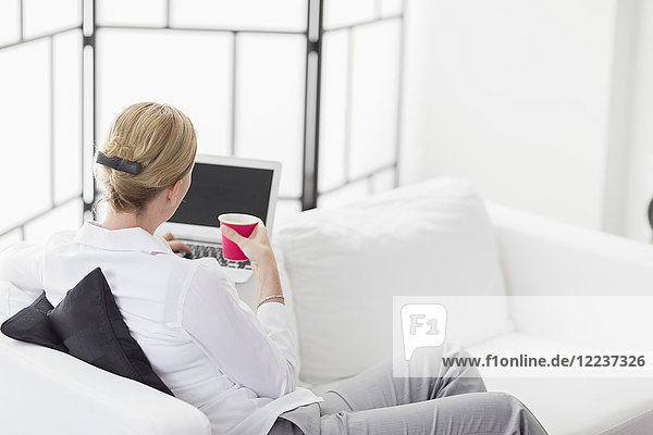 Frau benutzt Laptop im Wohnzimmer