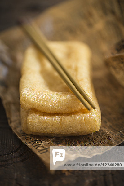 Gebratener Tofu mit Stäbchen auf Papier (Asien)