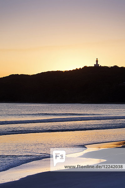 Silhouette des Leuchtturms von Cape Byron und sonnenbeschienener Strand bei Sonnenuntergang in Byron Bay in New South Wales  Australien