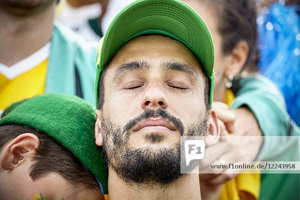 Fußballfan mit Kopf zurück und Augen geschlossen in Enttäuschung