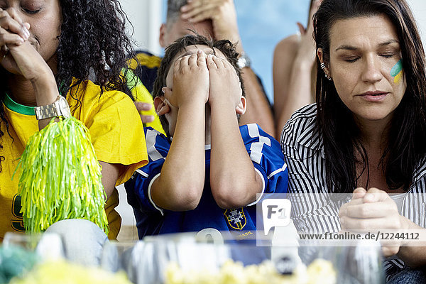 Brasilianische Fußballfans sehen verärgert aus  während sie das Spiel zu Hause verfolgen.