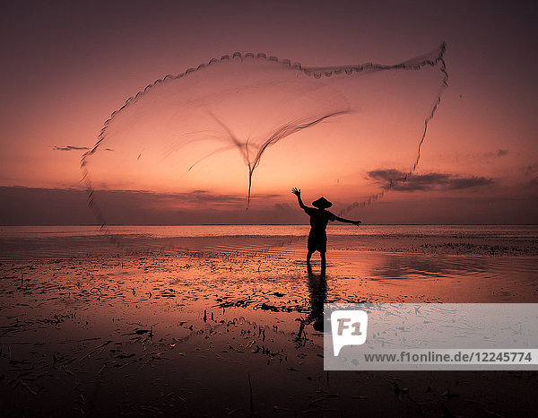 Sonnenaufgang Fischer wirft sein Netz aus  Bali  Indonesien  Südostasien  Asien