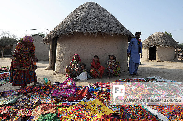 Pathan-Stammesfamilie vor einem traditionellen Lehmhaus (bhunga)  das ihre farbenfrohen Stammesstickereien zeigt  Jarawali  Kutch  Gujarat  Indien  Asien