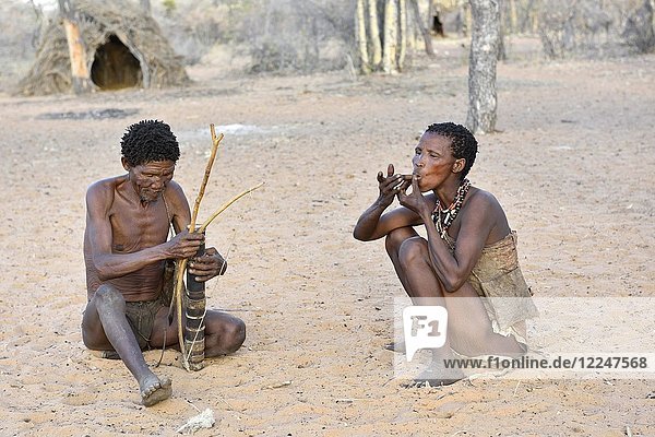 San man with bow and arrow and smoking woman  Bushman tribe  Kalahari  Namibia  Africa