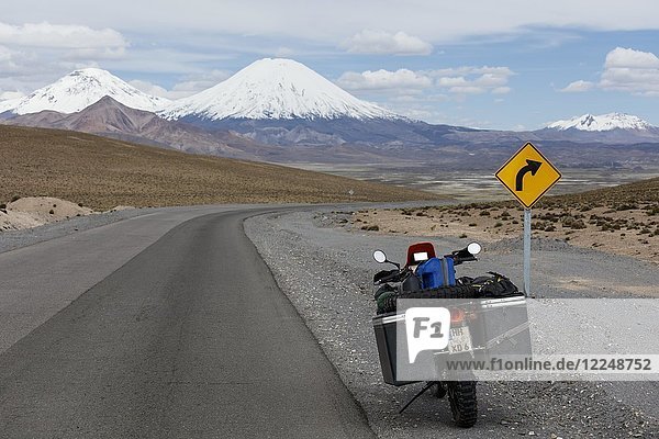 Schwer bepacktes Motorrad am Straßenrand hinter dem Vulkan Pomerape  Putre  Region de Arica y Parinacota  Chile  Südamerika
