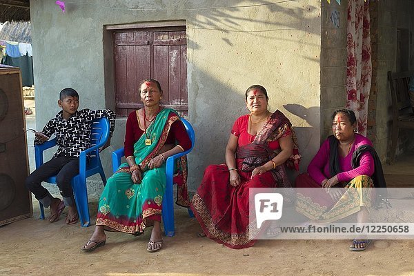 Nepalesische Frauen der ethnischen Gruppe der Tharu sitzen während einer Hochzeit vor einem Haus  Chitwan  Nepal  Asien
