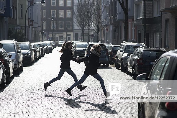Zwei Jugendliche laufen über eine Straße  Düsseldorf  Nordrhein-Westfalen  Deutschland  Europa