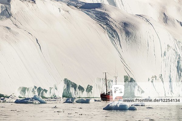 Rotes Boot vor einem gigantischen Eisberg  Westgrönland  Grönland  Nordamerika
