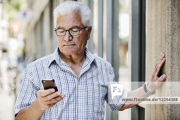 Grauhaariger Senior mit Brille und Smartphone in der Stadt  Köln  Nordrhein-Westfalen  Deutschland  Europa