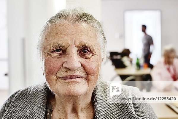 Demente Seniorin in einem Altenheim  unscharfes Pflegepersonal im Rücken  Deutschland  Europa