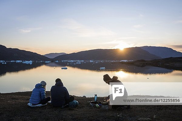 Trekkinggruppe am Fjordsee in bergiger Landschaft bei der Essenszubereitung  Abendstimmung  Westgrönland  Grönland  Nordamerika