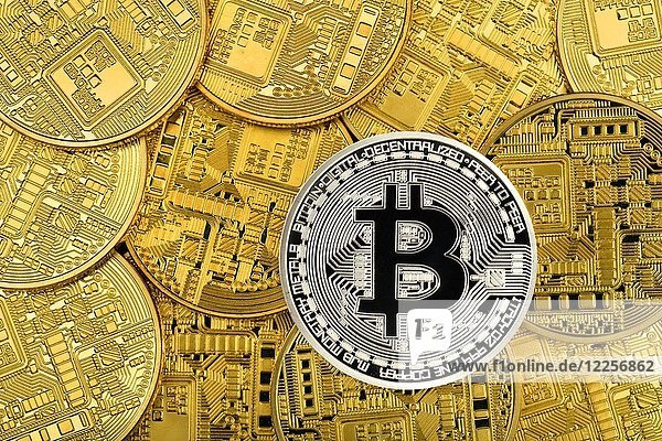 Symbolbild Kryptowährung  digitale Währung  Silbermünze Bitcoin auf Goldmünzen