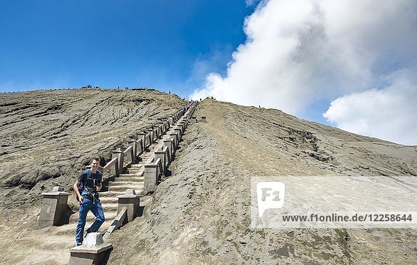 Young man on the stairs to the crater rim of the smoking volcano Gunung Bromo  National Park Bromo-Tengger-Semeru  Java  Indonesia  Asia