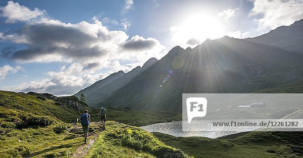 Hikers at the Unterer Giglachsee with morning sun  Schladminger Höhenweg  Schladminger Tauern  Schladming  Steiermark  Austria  Europe