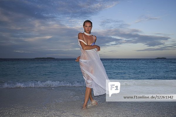 Young woman posing in wet white cloth on the beach at dusk  Fuvahmulah Island  Indian Ocean  Maldives  Asia