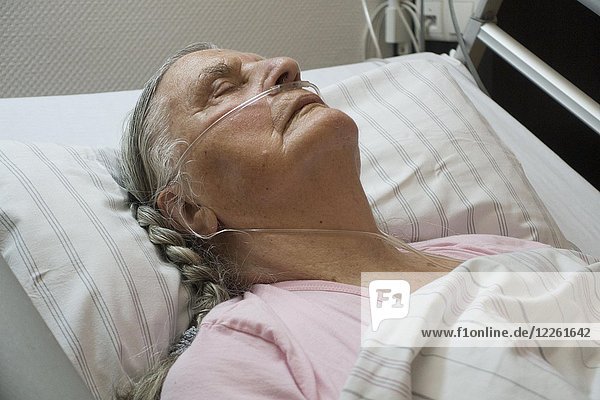 Sleeping senior citizen with respiratory tube in bed in hospital  Germany  Europe