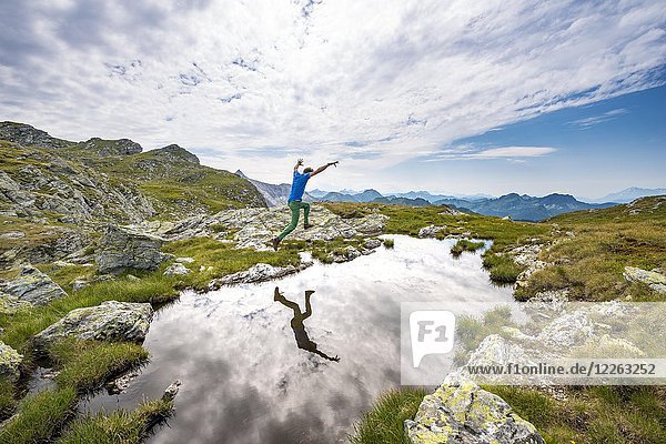 Wanderer springt  Spiegelung in einem kleinen See  Schladminger Höhenweg  Schladminger Tauern  Schladming  Steiermark  Österreich  Europa