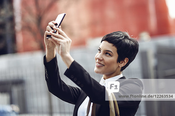 Porträt einer lächelnden jungen Geschäftsfrau  die sich mit dem Handy selbstständig macht.