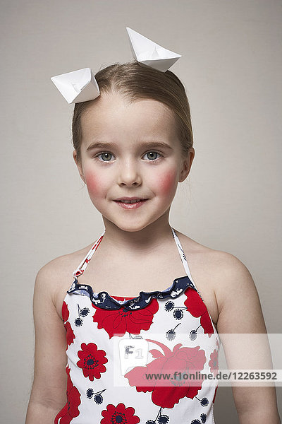 Porträt eines kleinen Mädchens mit zwei Papierbooten auf dem Kopf