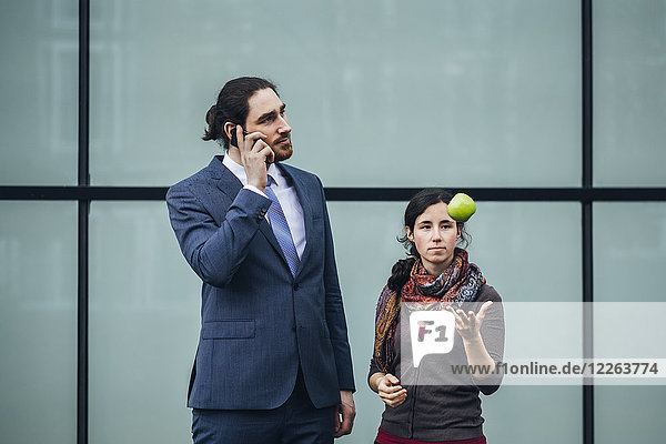 Businessman talking on cell phone and woman throwing an apple