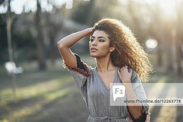 Portrait of young woman in a park at evening twilight