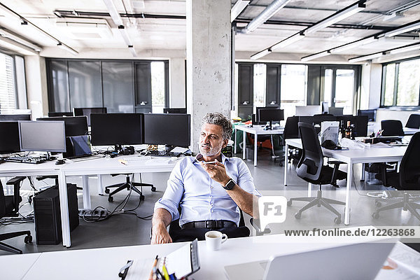 Reife Geschäftsleute sitzen am Schreibtisch im Büro mit Smartphone