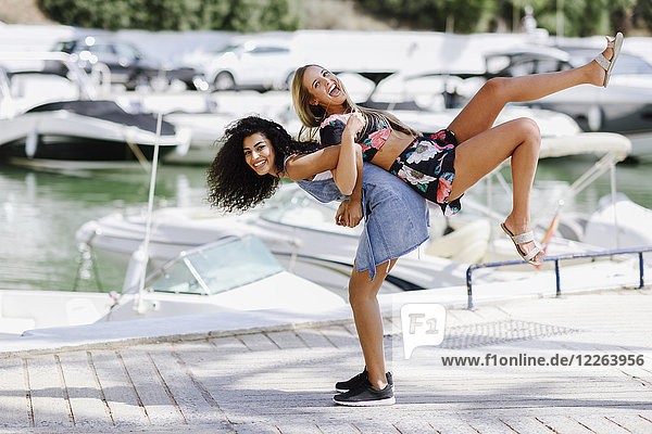 Two playful young women at waterfront promenade in summer