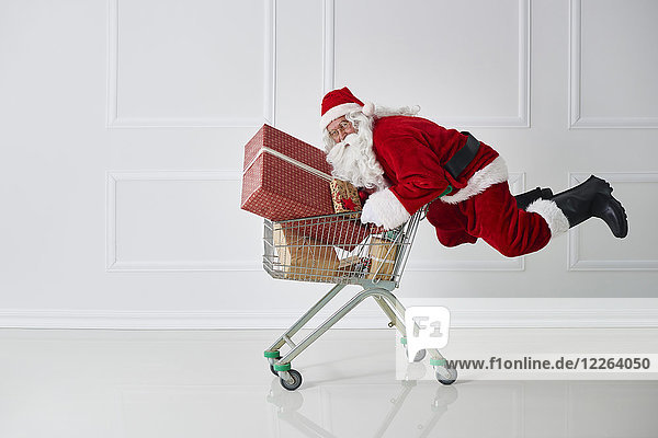 Weihnachtsmann mit Weihnachtsgeschenken mit Einkaufswagen