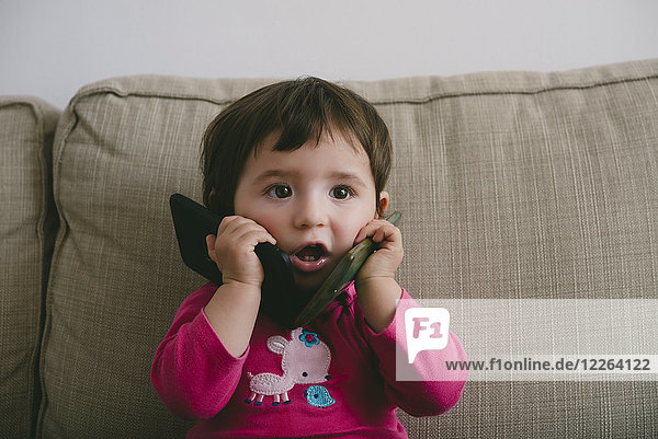 Kleines Mädchen spielt mit zwei Handys zu Hause
