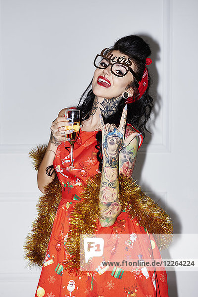 Portrait einer tätowierten Frau mit Champagnerglas mit Rock And Roll Schild