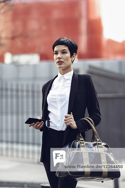 Porträt der modischen jungen Geschäftsfrau mit Handy und Tasche