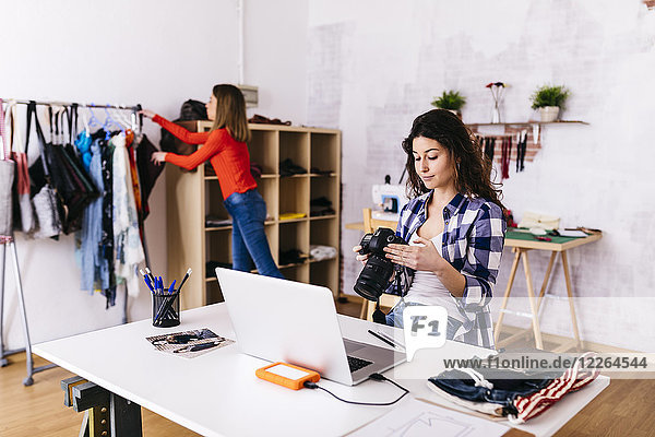 Fashion designer with camera and laptop in studio