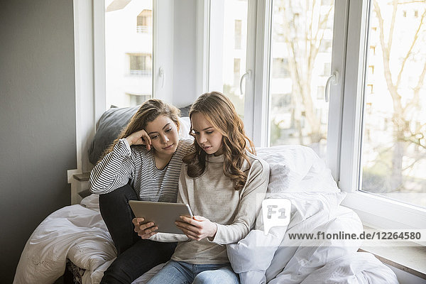 Two teenage girls using tablet at homne