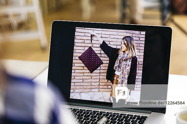 Photo of woman holding bag on laptop screen