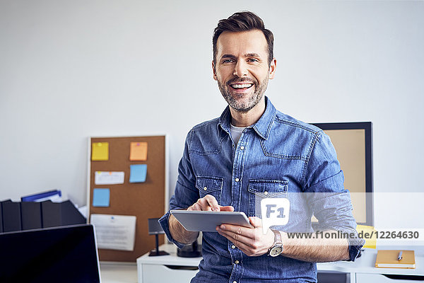 Portrait of smiling man using tablet in office