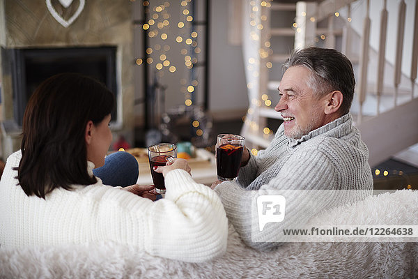 Happy mature couple with hot drinks in living room